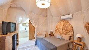 Un dormitorio con cama, mesitas de noche, televisor y aire acondicionado.