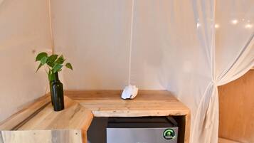 Una habitación pequeña con una mesa de madera, una planta, un objeto blanco colgando del techo y un refrigerador Hisense.