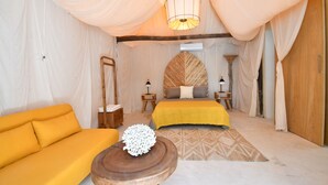 Una habitación con cama, sofá, mesa de madera y una lámpara colgante.