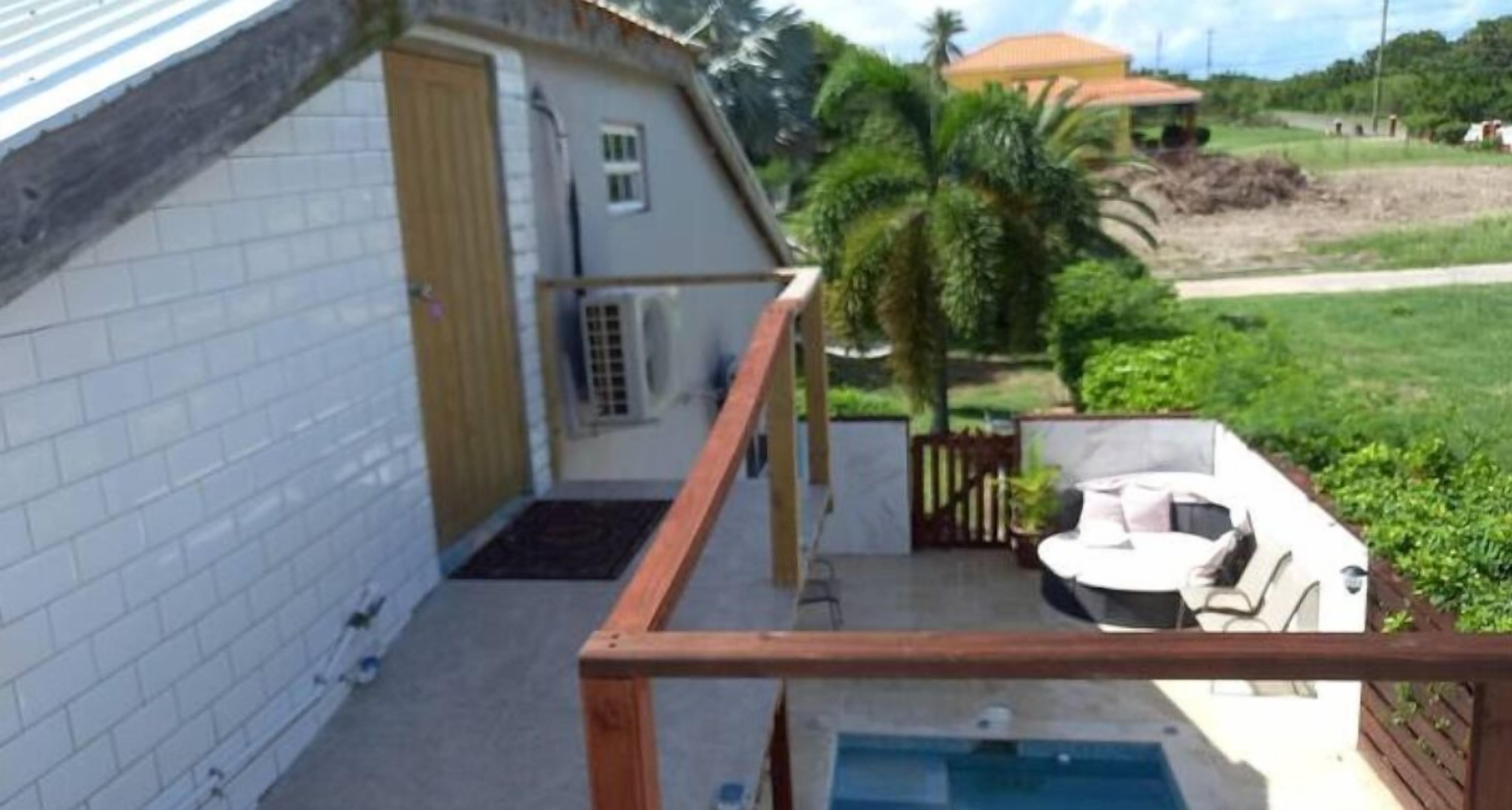 Una casa con un pequeño patio, piscina y terraza cercada.