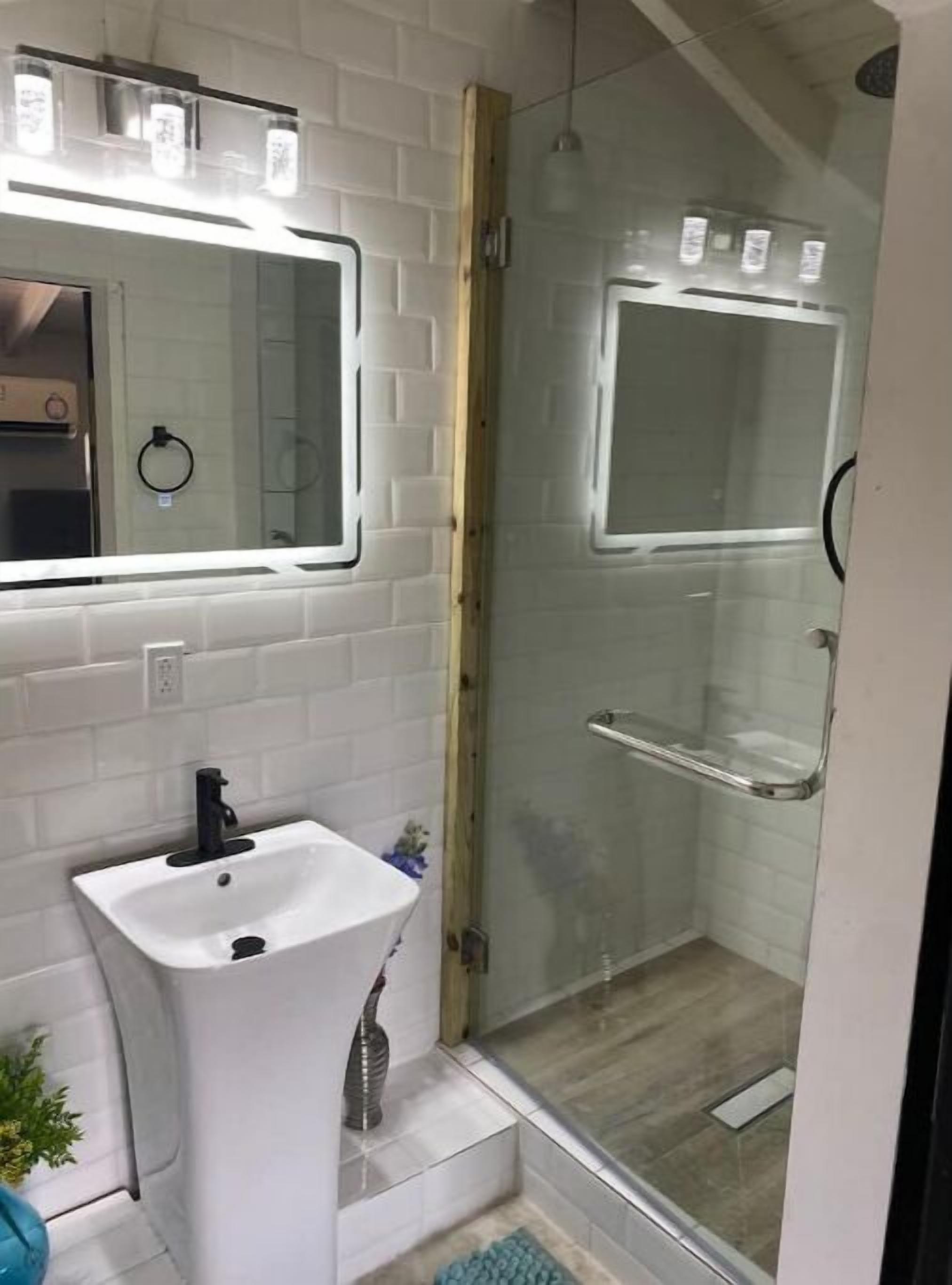 A bathroom with a white sink, mirror, and glass shower enclosure.