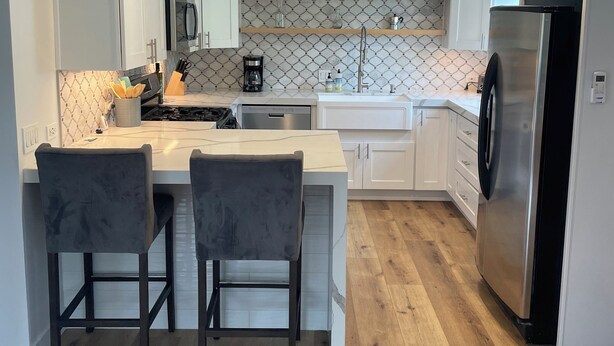Una cocina moderna con armarios blancos, un refrigerador de acero inoxidable y una encimera de madera.