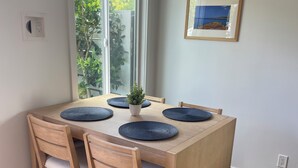 Un comedor con una mesa de madera, cuatro sillas y una planta en maceta.