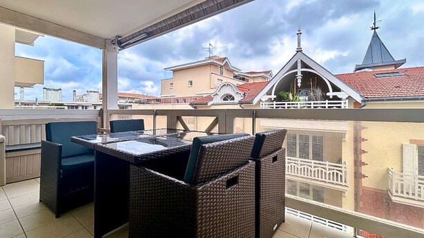 Een balkon met rieten meubels, een tafel en stoelen.