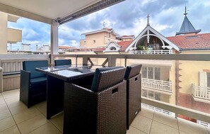 A balcony with wicker furniture, a table, and chairs. - T2, situé en centre-ville proche de la plage (ARCACHON)
