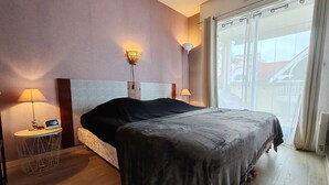 Een hotelkamer met een bed, bedlampjes, een digitale klok en een raam met gordijnen.