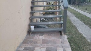 Una zona patio piastrellata con ringhiera in metallo e un secchio bianco.