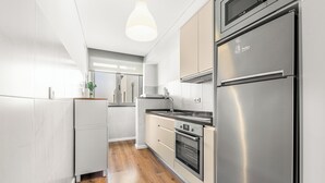 Een moderne keuken met roestvrijstalen apparatuur, houten vloeren en witte kasten.