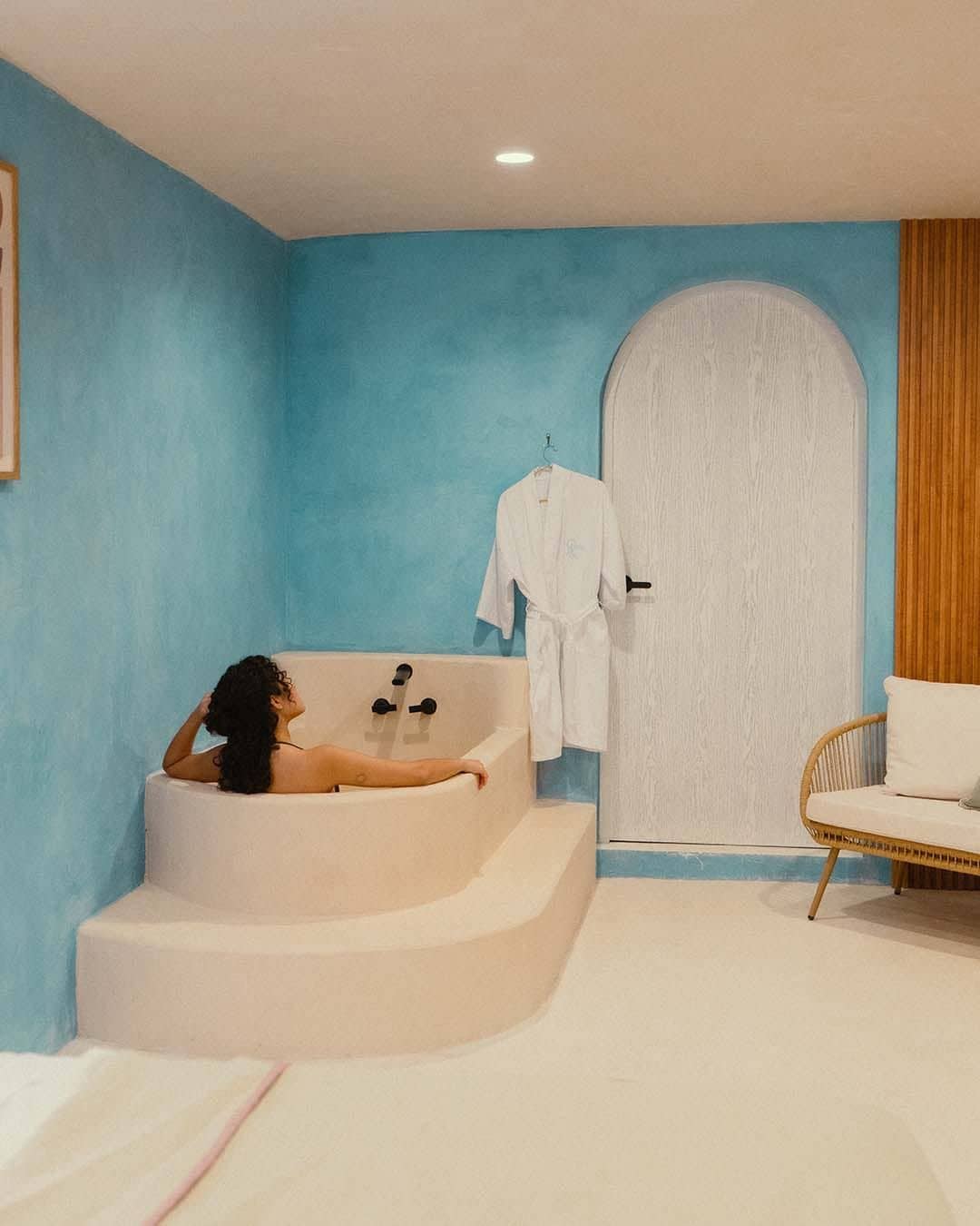 Une salle de bain avec une baignoire, une porte blanche et une chaise en osier.