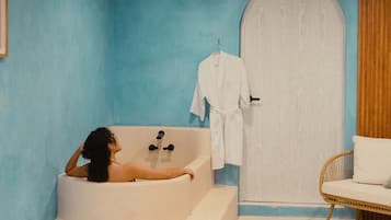 Une salle de bain avec une baignoire, une porte blanche et une chaise en osier.