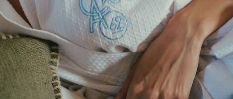 Primer plano de una mano sobre tela blanca con un emblema circular y el número '62' a la vista.