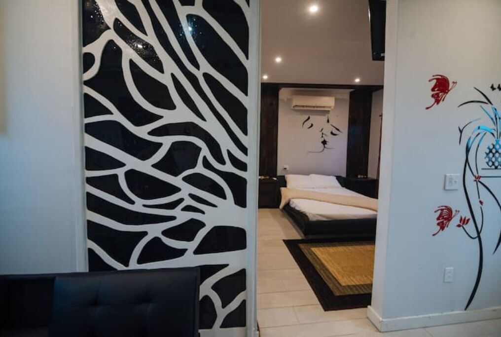 A modern bedroom with a bed, a decorative wall panel, and a nightstand.