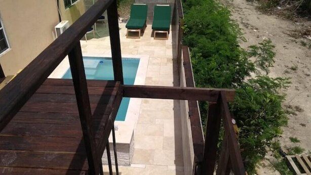 Eine Holzterrasse mit Pool und Liegestühlen.