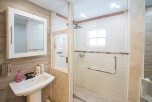 A bathroom with a white sink, mirror, and glass shower enclosure.