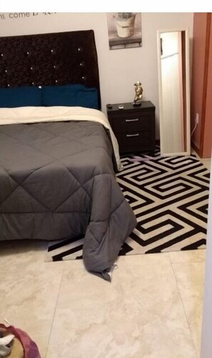 A bedroom with a bed, a dresser, and a patterned rug.