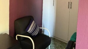 Une pièce avec une chaise noire, une armoire blanche et une petite table.