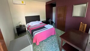 Une chambre d’hôtel équipée d’un lit, d’un bureau, d’une chaise, d’une armoire et d’un appareil de climatisation.
