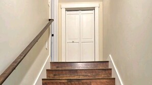 Una scala in legno con corrimano che conduce a una porta bianca in alto.