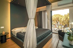 A modern bedroom with a large bed, a small table, and a view of the outdoors.
