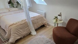 A bedroom with a canopy bed, a round rug, a brown armchair, and a small side table with a plant.