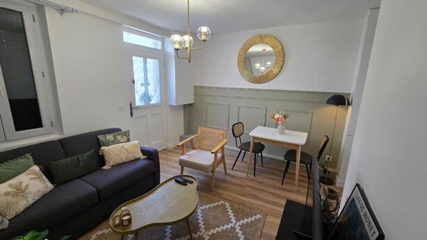 A living room with a sofa, coffee table, and chairs, a dining area with a table and chairs, and a kitchen with a stove.