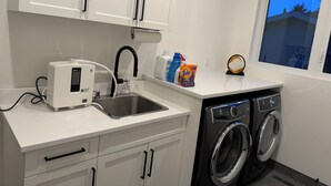 A modern kitchen with a built-in washing machine and a sink. - Vacation home in Sechelt (Sechelt)