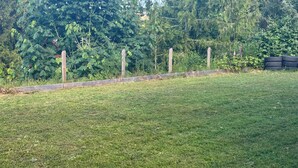 A grassy outdoor area with a wooden fence and trees in the background. - Vacation home in Sechelt (Sechelt)