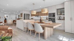 Een moderne keuken met een centraal eiland, hangende verlichting en witte kasten.