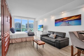 Ein modernes Hotelzimmer mit einem Bett, einer Ledersofa, einem kleinen Tisch und einem Fernseher.