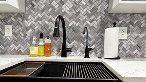A kitchen with a black sink, a herringbone-patterned backsplash, and a white countertop. - 2 Bedroom 2 Bath Condo (Tulsa)