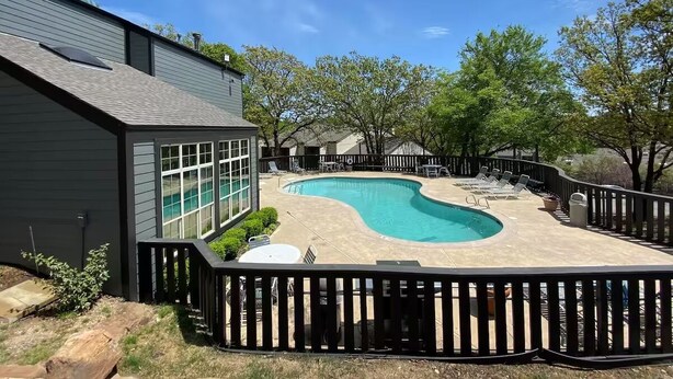 A backyard with a swimming pool, surrounded by a wooden deck and a fence. - 2 Bedroom 2 Bath Condo (Tulsa)