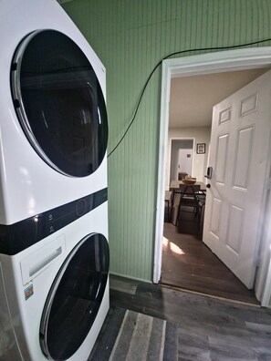 Laundry room with a front-loading washing machine and access to a dining area.