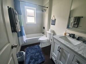 Bathroom features a bathtub, toilet, and sink with a countertop.