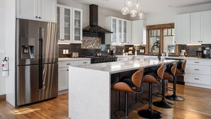 Una cocina moderna con una isla grande, electrodomésticos de acero inoxidable y taburetes de bar.