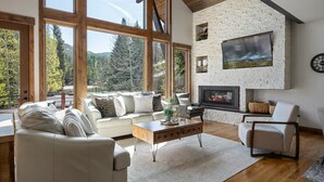 Un salón amplio con chimenea, ventanas grandes y una pared de piedra.
