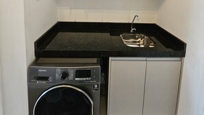 Cocina compacta con lavadora y secadora integradas, un lavaplatos y armarios superiores.