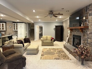 A spacious living room with a fireplace, a ceiling fan, and a kitchen area visible through an open door. - Spacious guest apartment to enjoy. Only 12 Minutes from Liberty University. (Forest)