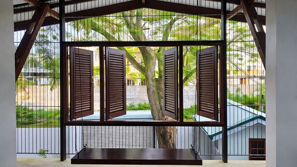 A room with a large window, a swing, and a view of greenery outside.