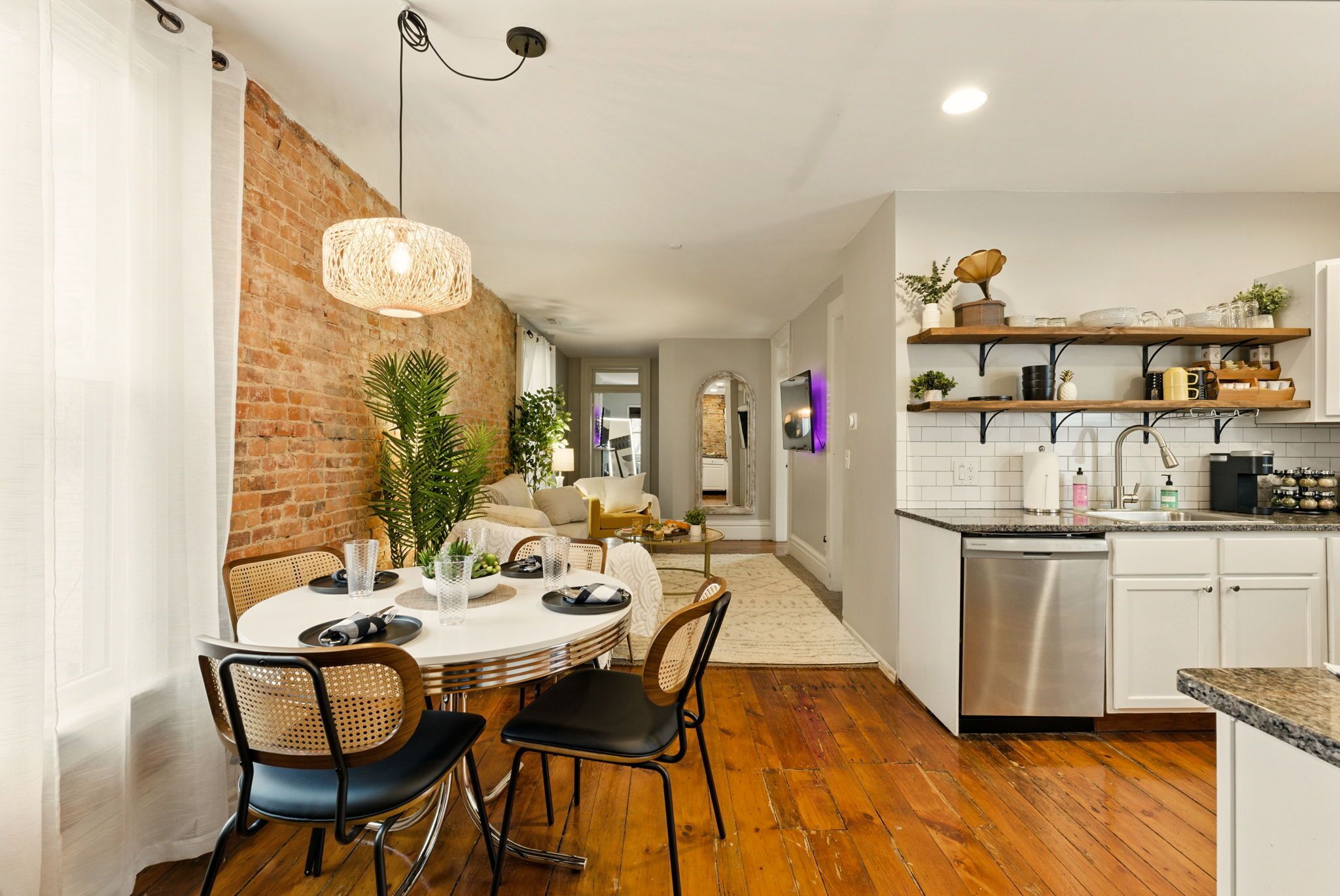 Una cocina moderna con armarios blancos, lavavajillas de acero inoxidable y repisas de madera.