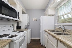 Enjoy cooking in this well-equipped kitchen with a stove, microwave, refrigerator, and double sink.