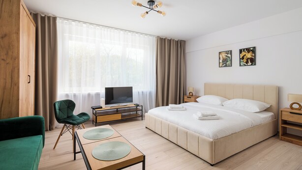 A hotel room with a bed, a TV, a desk, a chair, and a green sofa.