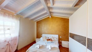 A bedroom with a bed, bedside table, and a window with curtains. - Maison Belvedere By Bookinggardalake (Manerba del Garda)