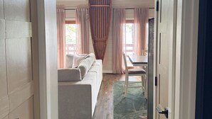 A narrow hallway leading to a living area with a sofa, a dining table, and a large wooden object hanging from the ceiling. - Lake House Cabin 3BR/2BA Sleeps 6 Water Front With Private Boat Dock for Fishing (Cedar Bluff)