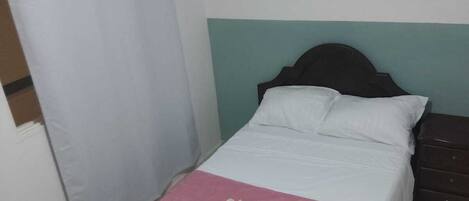 A bedroom with a bed, a nightstand, a curtain, and three wall art pieces.