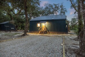 A rustic cabin with a metal roof, wooden exterior, and a gravel driveway.