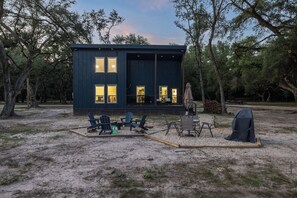 A modern cabin with a deck, outdoor seating, and a barbecue area.