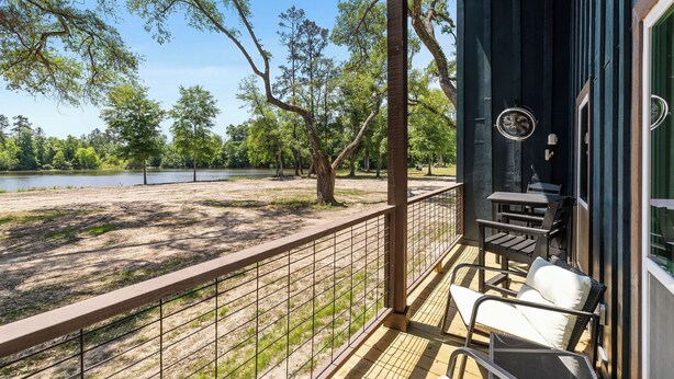 Un balcon donnant sur un lac et des arbres, avec une table et une chaise.