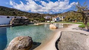A clear pool with rocks, a white building, and a mountainous backdrop. - Cortijo Rural Fandango 3 - Pool and Mountain (Almuñecar)