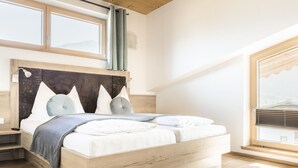 A bedroom with a wooden bed, a window with a view, and a bedside table.