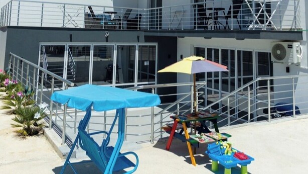 A multi-story hotel with balconies, air conditioning units, and outdoor seating.